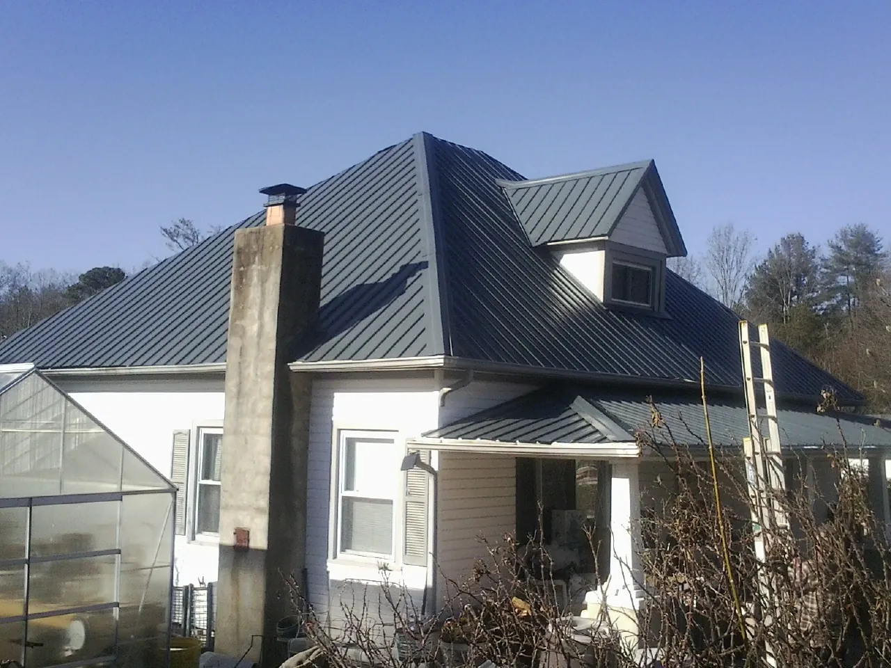 Dark blue standing seam metal roof on a white farmhouse with dormer — Slate & Tile Roof Repair by Roofing Brothers in Atlanta