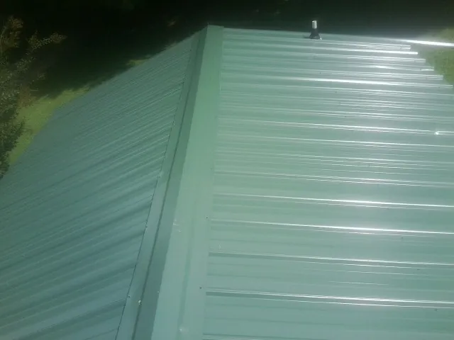 New green metal panels meeting at the ridge of a roof — Flat Roof Repair work by our crew in Atlanta