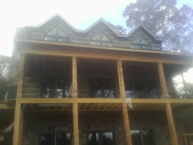 Dormers and porch framing on a large log home under construction — Roof Coating work by our crew in Atlanta