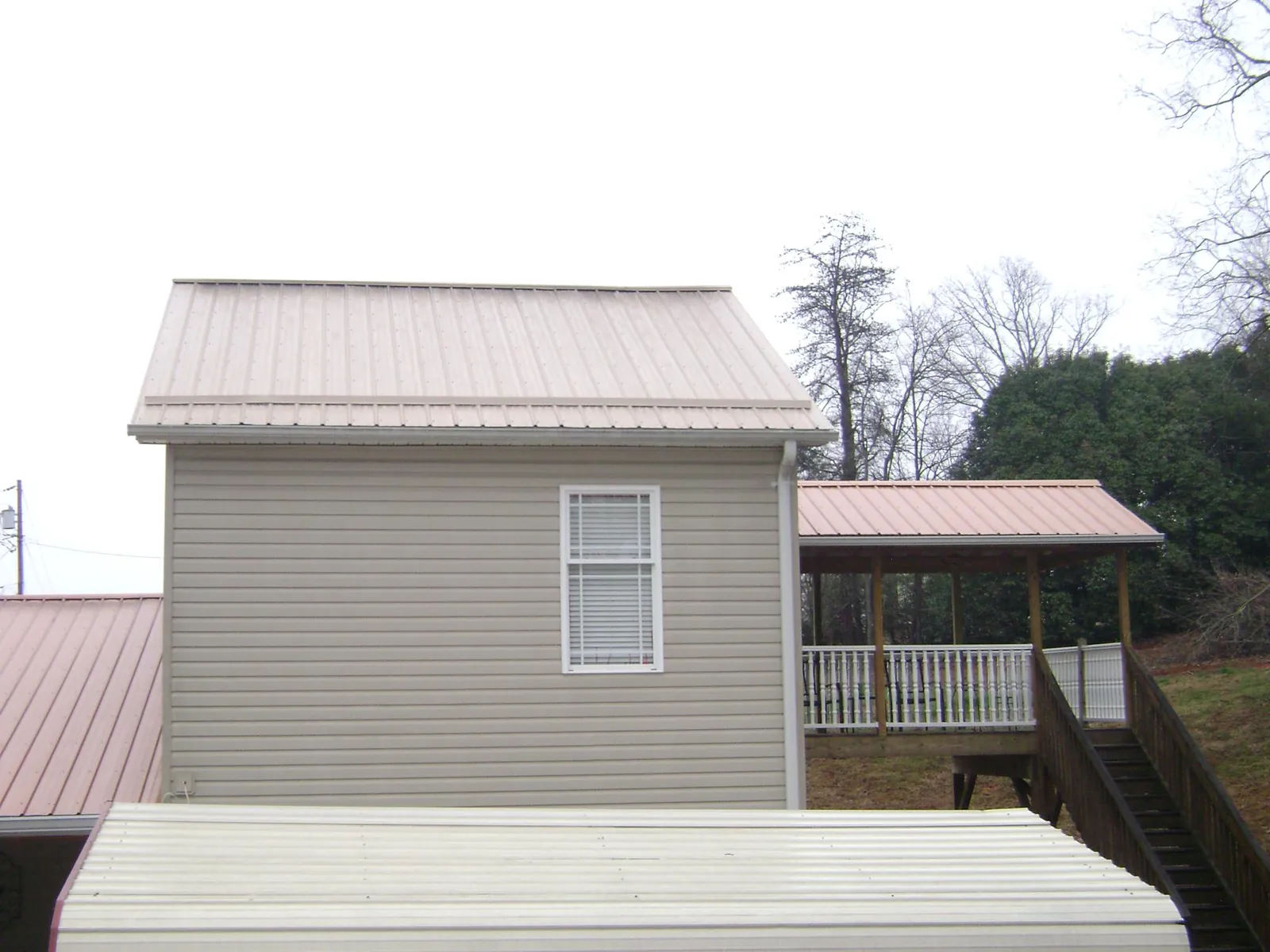 Tan metal roofs on a two story addition and attached porch, from a Roof Replacement job in Atlanta