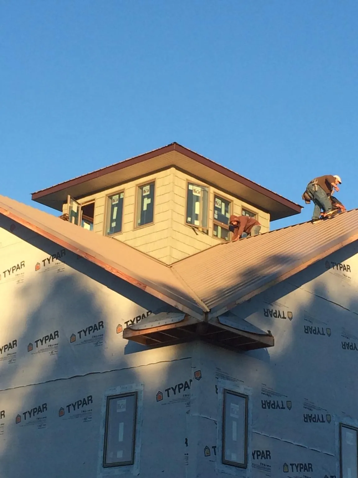 Roofers working around a rooftop cupola on a new metal roof at sunset — Roof Waterproofing in Atlanta by Roofing Brothers